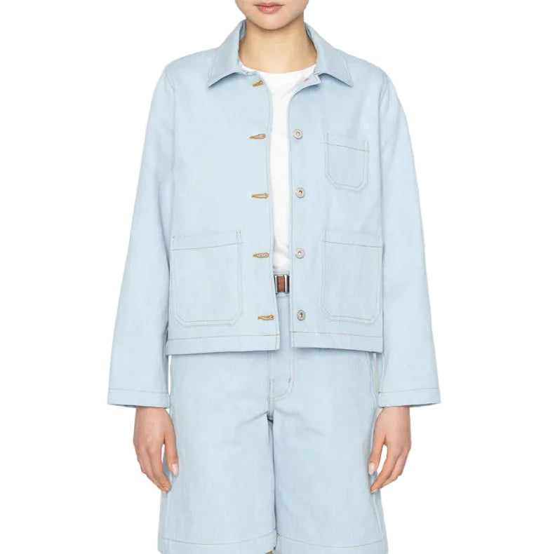 Person wearing a light blue denim jacket and pants on a white background