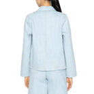 Person wearing a light blue denim jacket and shorts on a white background