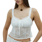 Model in a white camisole with delicate floral embroidery on a white background