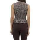 Woman wearing a patterned sleeveless top and brown capri pants on a white background
