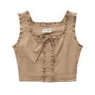 A sleeveless cropped top in a warm taupe-beige color, featuring delicate ruffle trim along the scoop neckline, tie-front detail, and buttoned ruffle placket. The brand label 'LE JEAN' is visible at the inner neckline.
