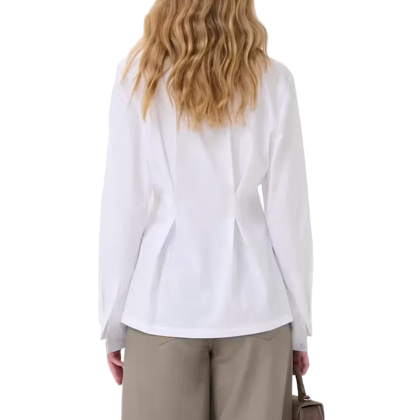A woman is shown from behind wearing a white long-sleeve blouse and wide-leg taupe trousers, holding a small brown handbag against a plain white studio background.