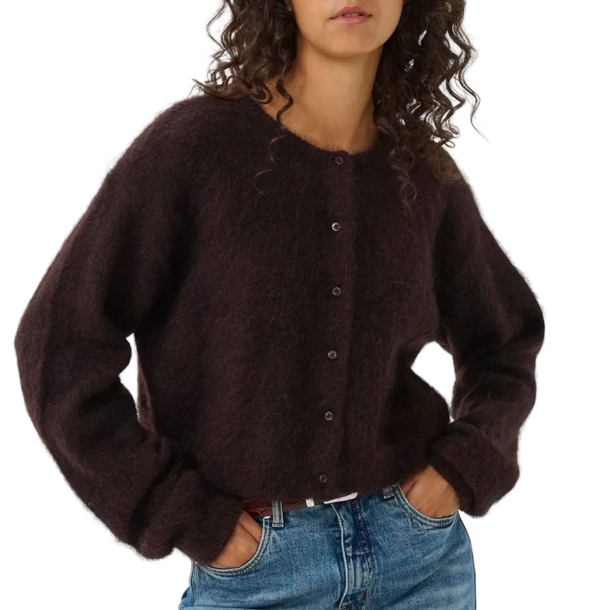 Woman wearing a dark brown cardigan and blue jeans against a white background
