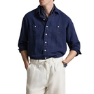 Man wearing a navy shirt and white pants against a neutral background