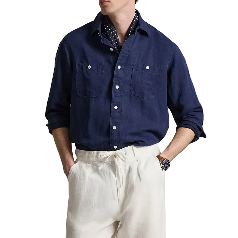 Man wearing a navy shirt and white pants against a neutral background