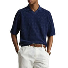 Person wearing a blue polo shirt and white shorts on a plain background
