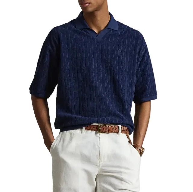 Person wearing a blue polo shirt and white shorts on a plain background