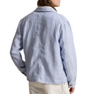 Person wearing a light blue striped shirt and white cap, standing against a white background