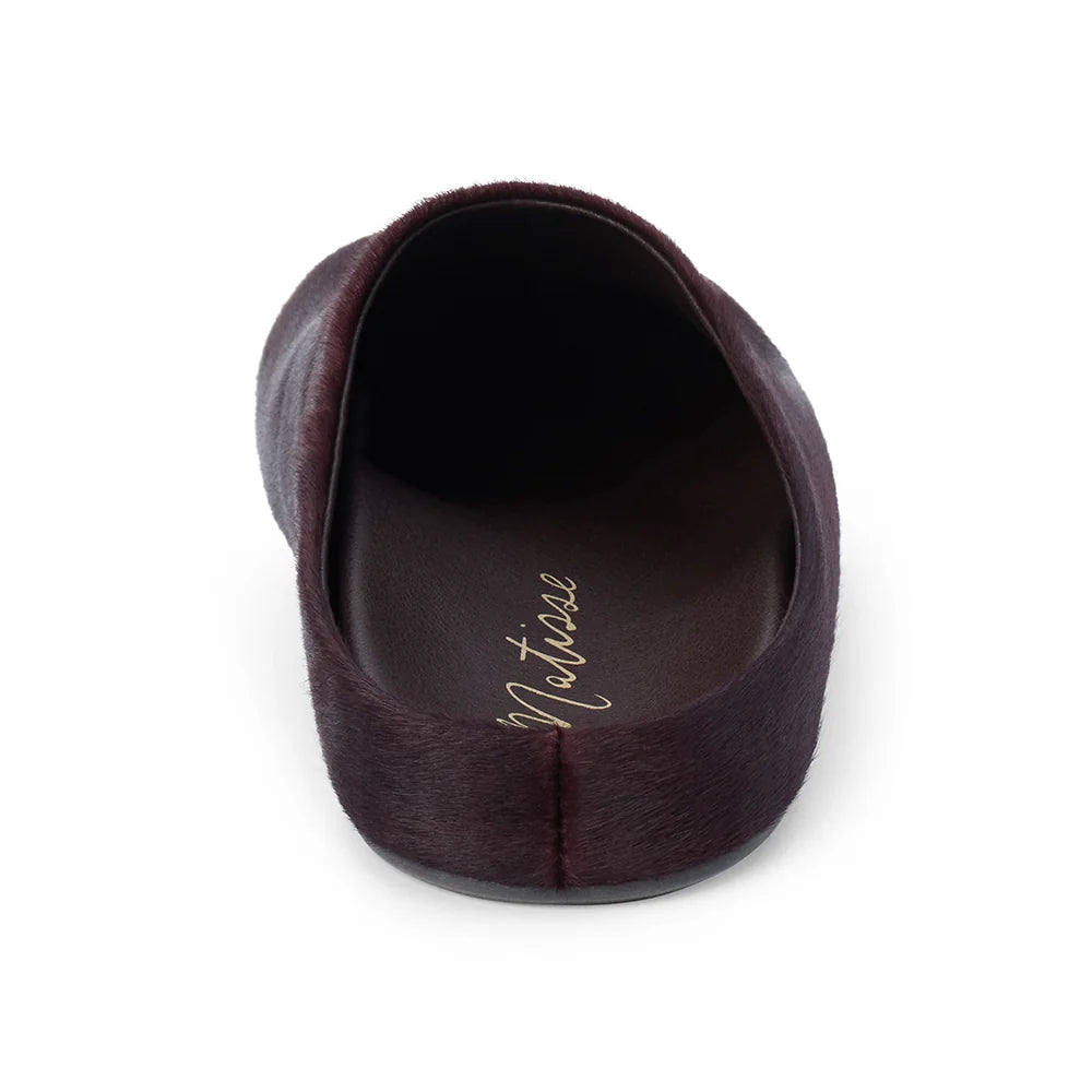 A single dark plum-colored slip-on shoe shown from a top-down view on a white background, featuring a textured finish and the brand name 'Matisse' printed in gold on the insole.