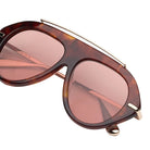 Tortoise sunglasses with red lenses and gold detailing on a white background