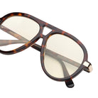 Tortoise framed sunglasses with yellow lenses and gold accents on a white background