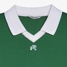 Close-up of a green polo with logo at the chest on a white background
