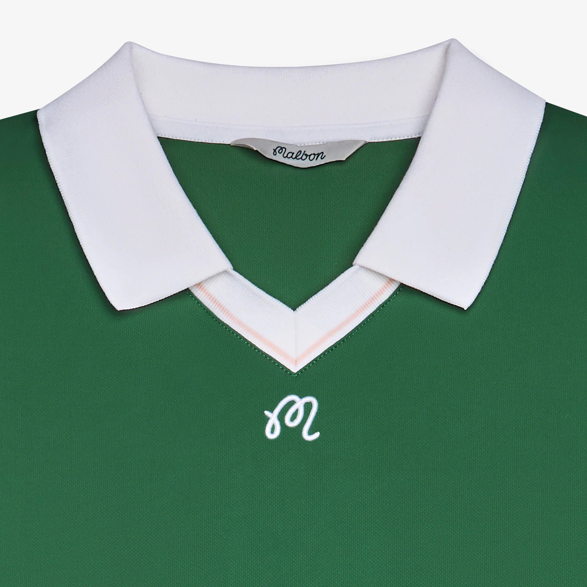 Close-up of a green polo with logo at the chest on a white background
