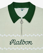 Close-up of a green knit polo with an embroidered 'Malbon' logo across the chest on a white background