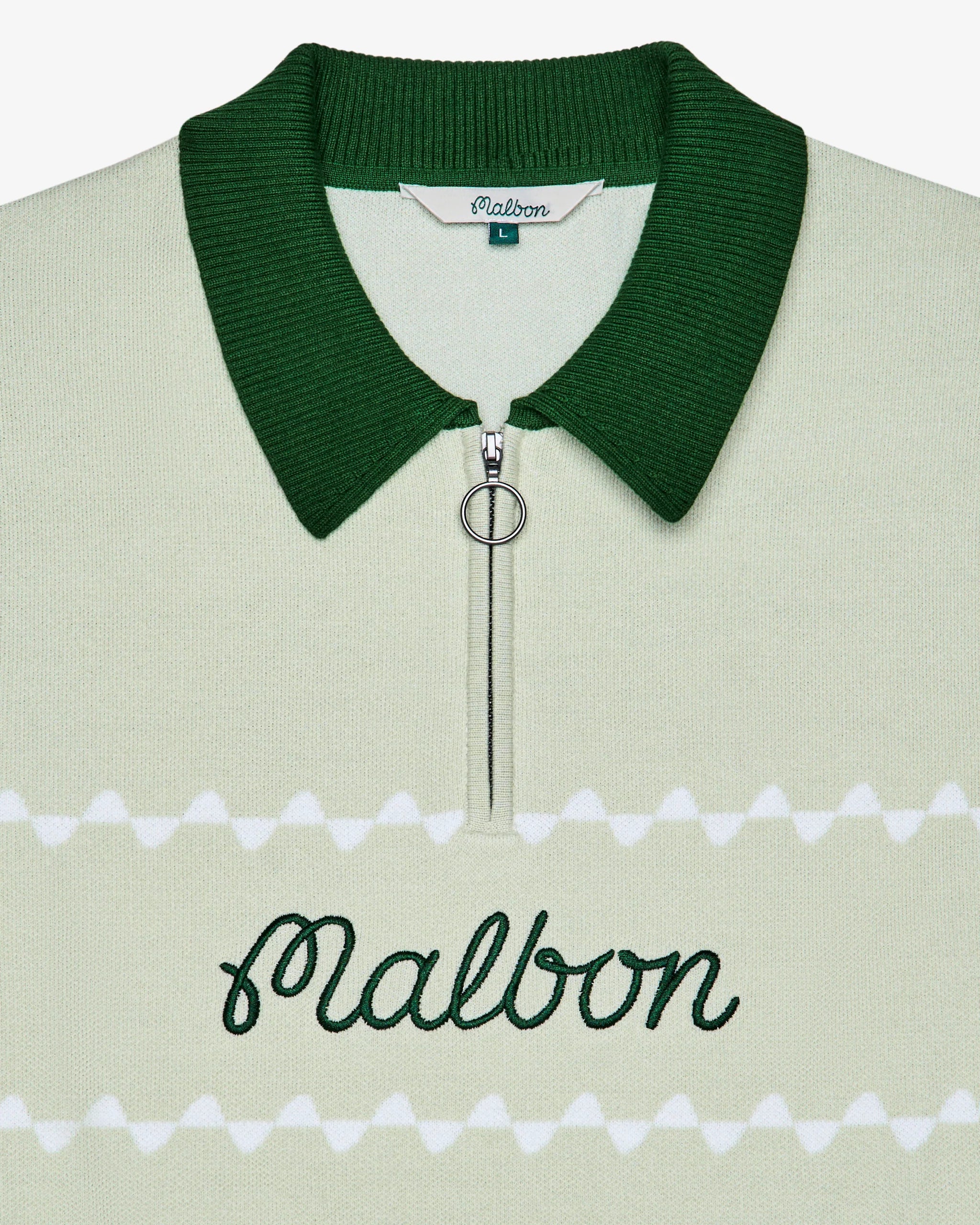 Close-up of a green knit polo with an embroidered 'Malbon' logo across the chest on a white background