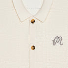 Close-up of the collar of a cream knit cardigan on a white background