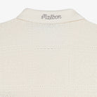 Close-up of the collar of a cream knit cardigan on a white background