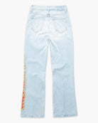 Light wash blue denim jeans shown from the back, featuring a colorful vertical flame graphic print in red, yellow, and green on the left leg.