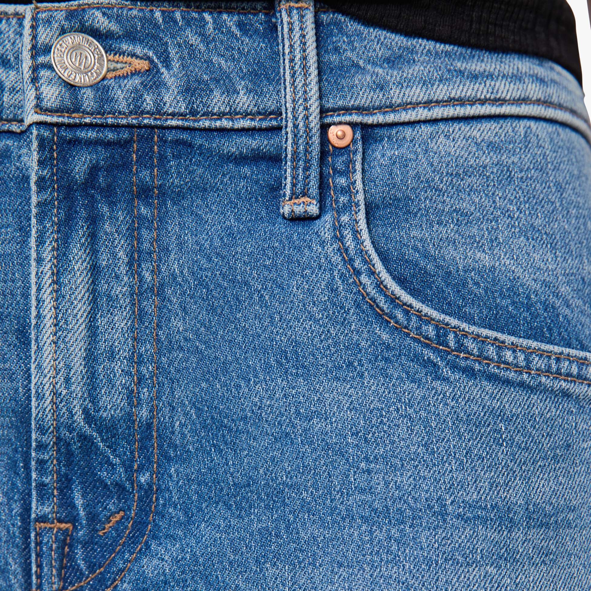 Close-up of blue jeans with a brand logo on the button area.