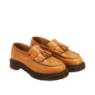 A pair of tan leather tassel loafers with dark brown soles, photographed on a clean, white background.