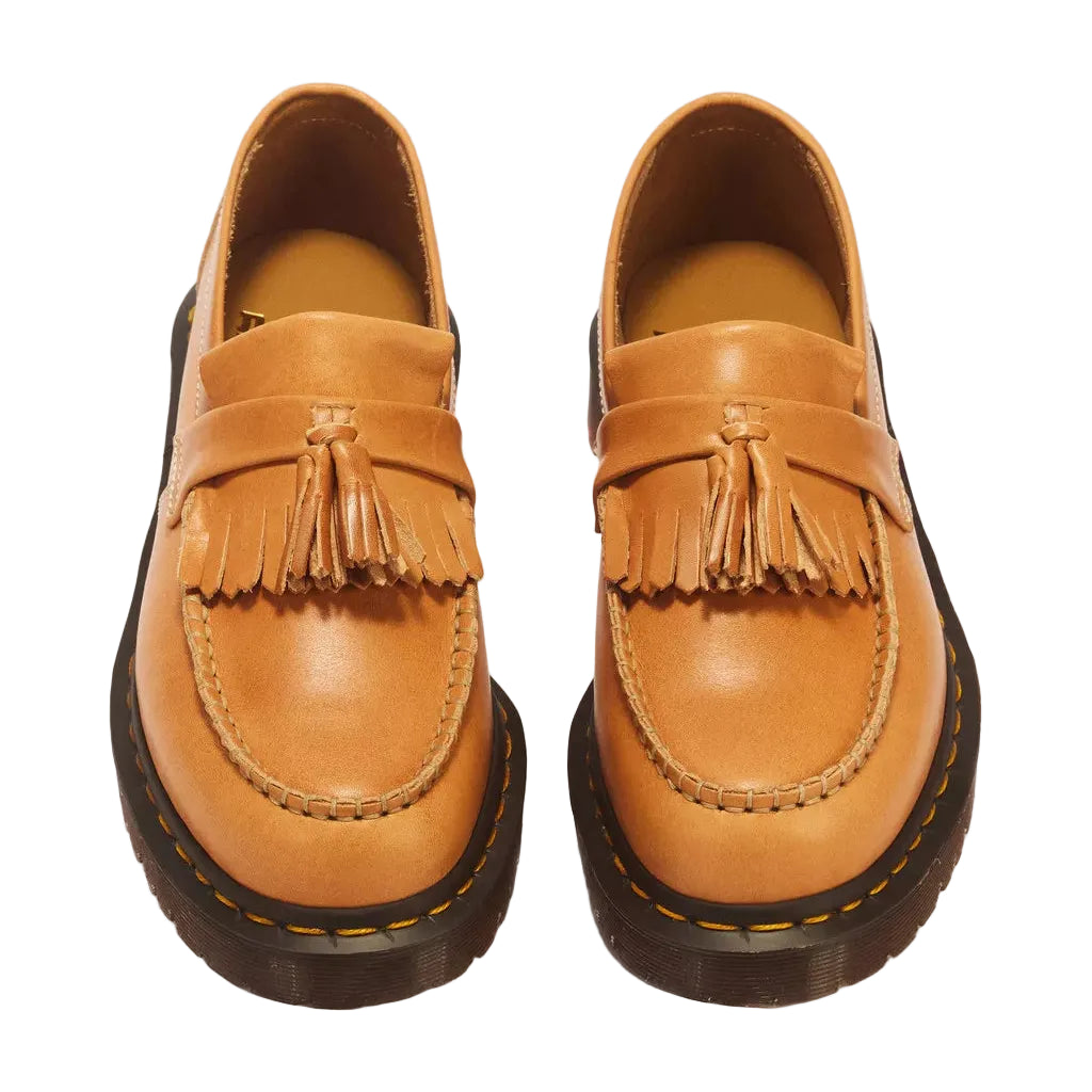 A pair of tan leather tassel loafers with dark brown soles, photographed from a top-down angle on a white background.