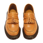A pair of tan leather tassel loafers with dark brown soles, photographed from a top-down angle on a white background.