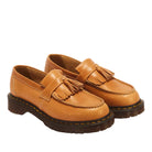 A pair of tan leather tassel loafers with dark brown soles, photographed on a white background.