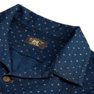 Close-up of a dark navy blue collared shirt with a small gold star pattern, featuring a brown button and a visible RRL neck label.