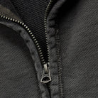 Close-up of a dark gray zippered knit garment, showing the zipper pull and ribbed fabric texture.