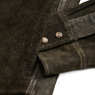 Close-up of a vintage black suede or nubuck jacket with metal snap buttons on a flap pocket, set against a plain white background.