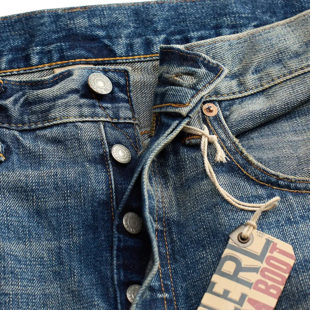 Close-up of a blue denim jeans with a brand tag on a blue background