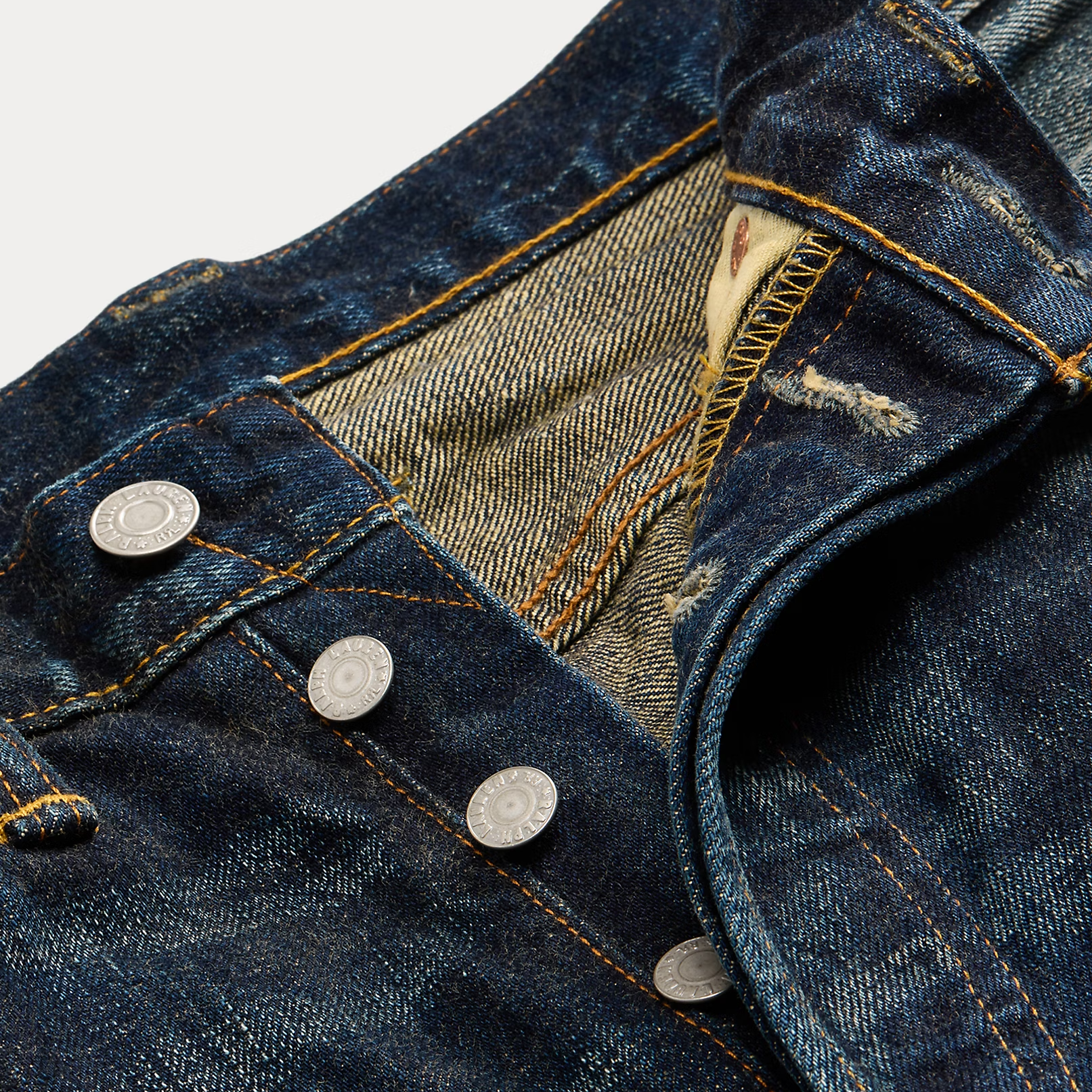 Close-up of a blue denim jeans with buttons and a worn-in look.