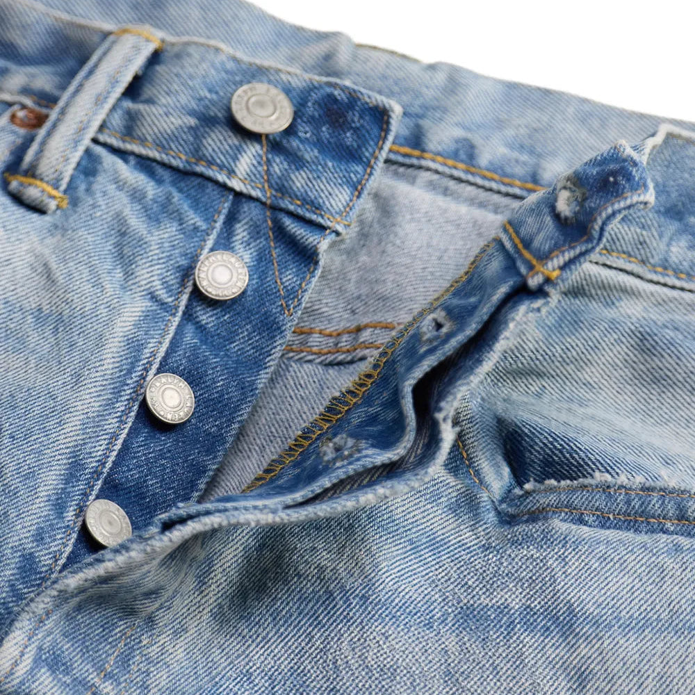 Close-up of a pair of light blue denim jeans showing the button fly, belt loops, and front pocket details.
