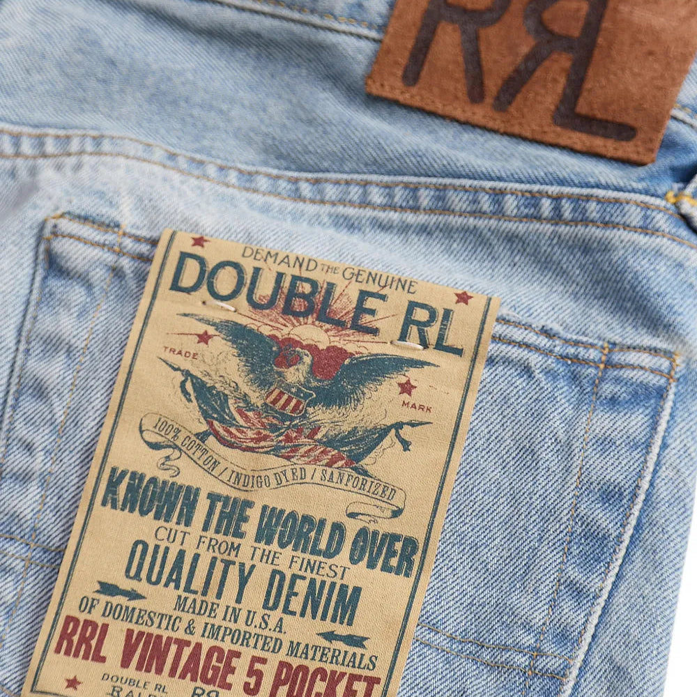 Close-up of the back pocket of light blue denim jeans showing a large vintage-style paper patch that reads 'DOUBLE RL' and 'RRL VINTAGE 5 POCKET,' plus a brown leather patch with 'RL' near the waistband.