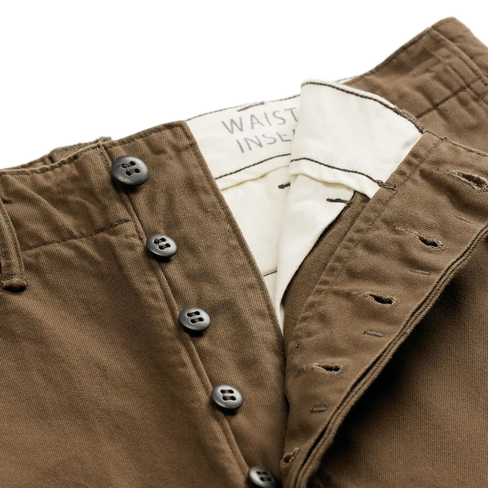 Close-up of brown pants showing a buttoned waistband, dark buttons, and a cream inner label that reads 'WAIST INS.