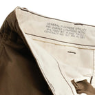 Close-up of the waistband of dark brown utility pants, showing the interior lining and printed technical specifications on the inside waistband.