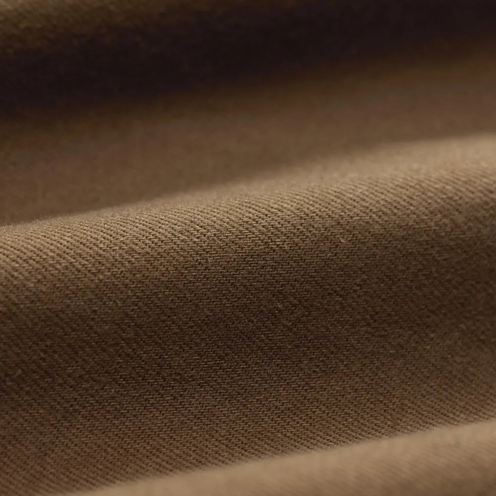 A close-up of draped brown fabric with soft folds and a fine woven texture.