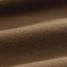 A close-up of draped brown fabric with soft folds and a fine woven texture.