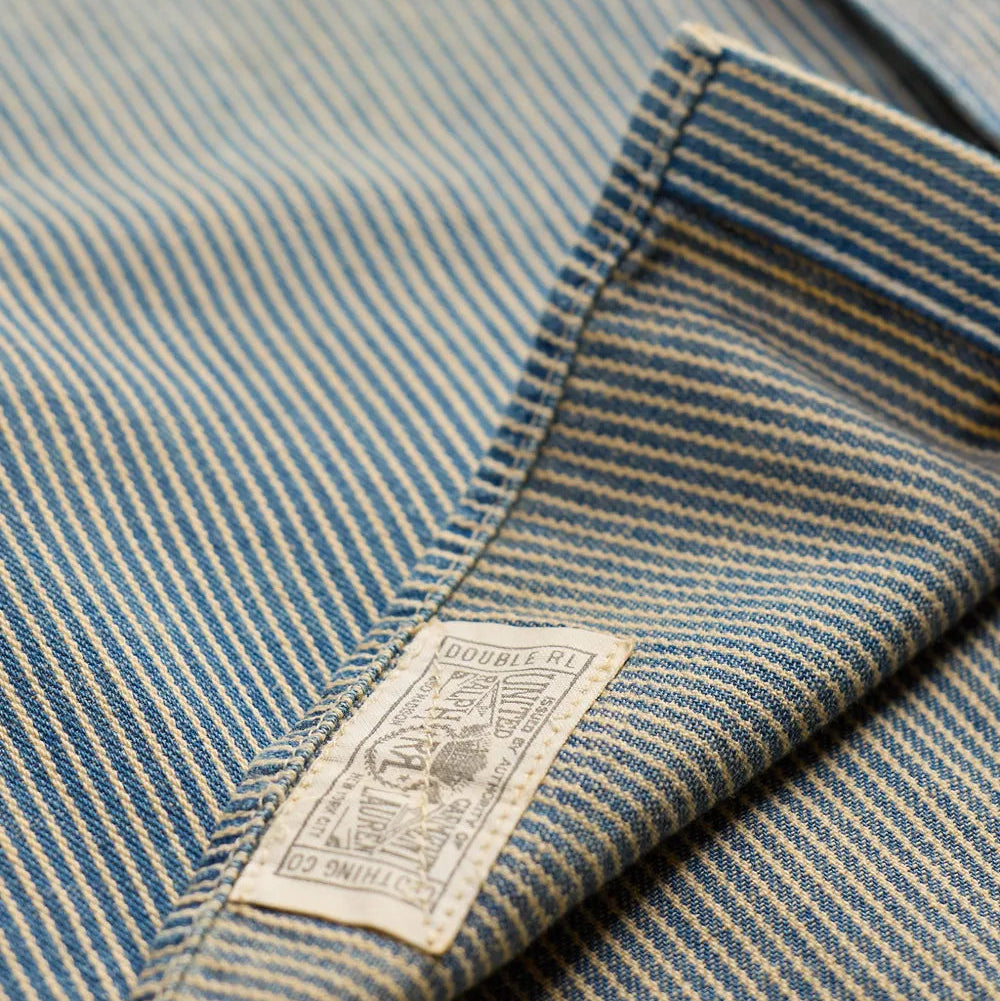 Close-up of a striped blue and beige garment fabric with a sewn-on brand label reading 'DUNHILL EST. 2011'.