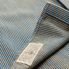 Close-up of a striped blue and beige garment fabric with a sewn-on brand label reading 'DUNHILL EST. 2011'.