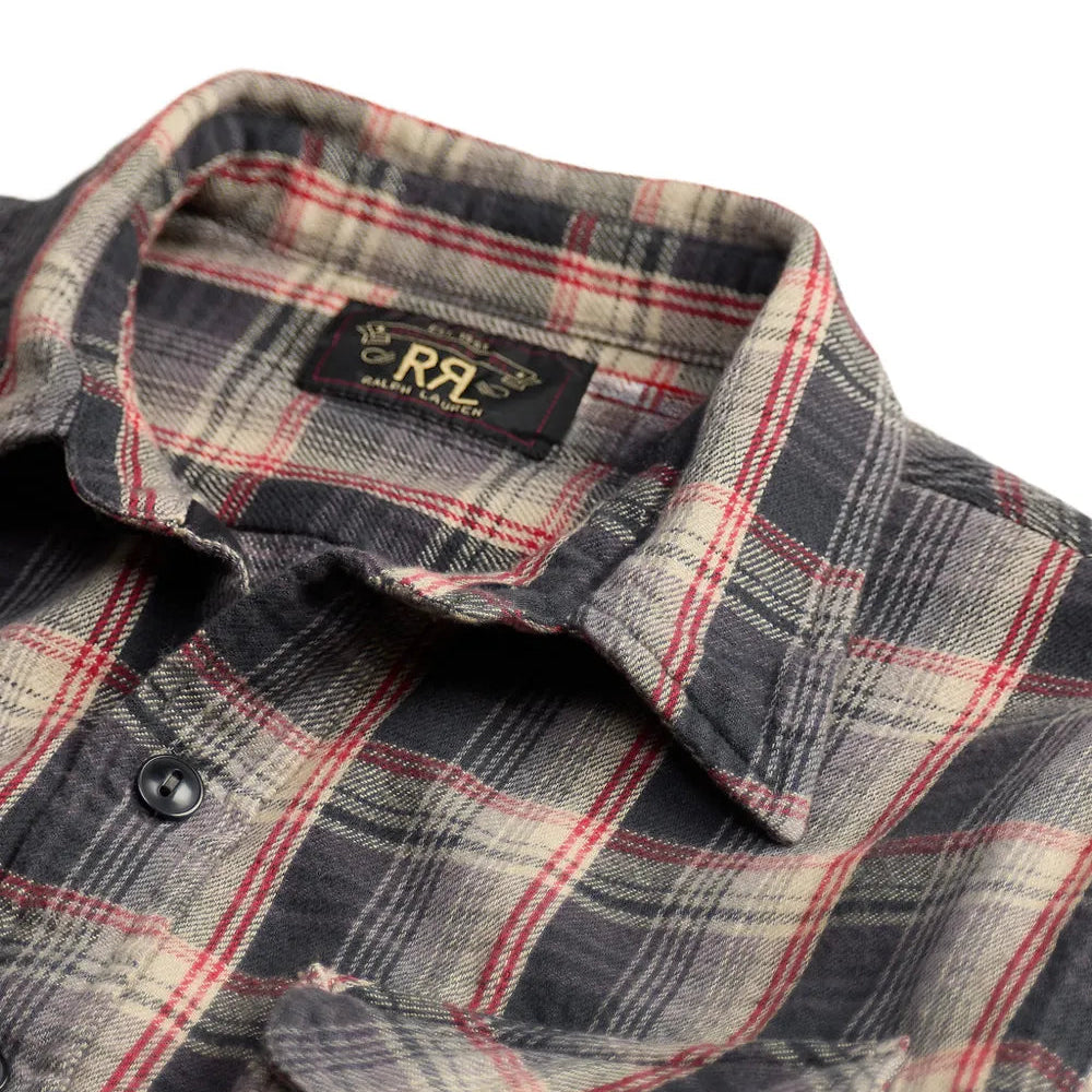 A close-up of a plaid button-up shirt collar and upper chest area. The fabric has a dark gray and beige base with red and white plaid lines.