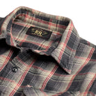 A close-up of a plaid button-up shirt collar and upper chest area. The fabric has a dark gray and beige base with red and white plaid lines.