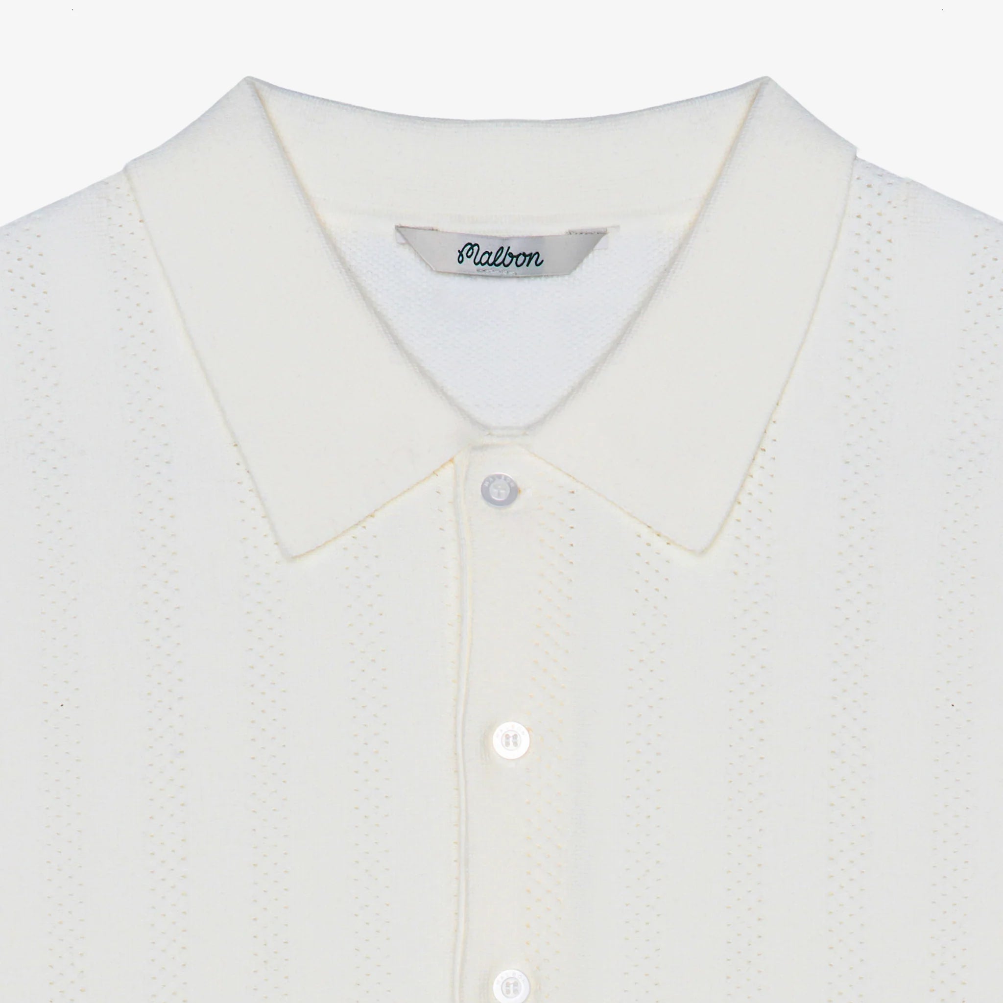 Close-up of a white textured knit polo shirt with a collar and white buttons, showing the 'Malbon' brand label inside the neck.