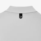 Close-up of the back collar of a light gray polo shirt, featuring a black fabric label with a white circular logo.