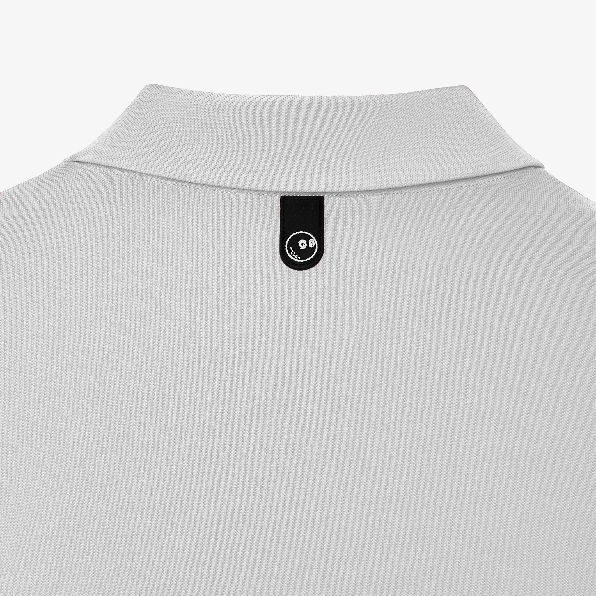 Close-up of the back collar of a light gray polo shirt, featuring a black fabric label with a white circular logo.
