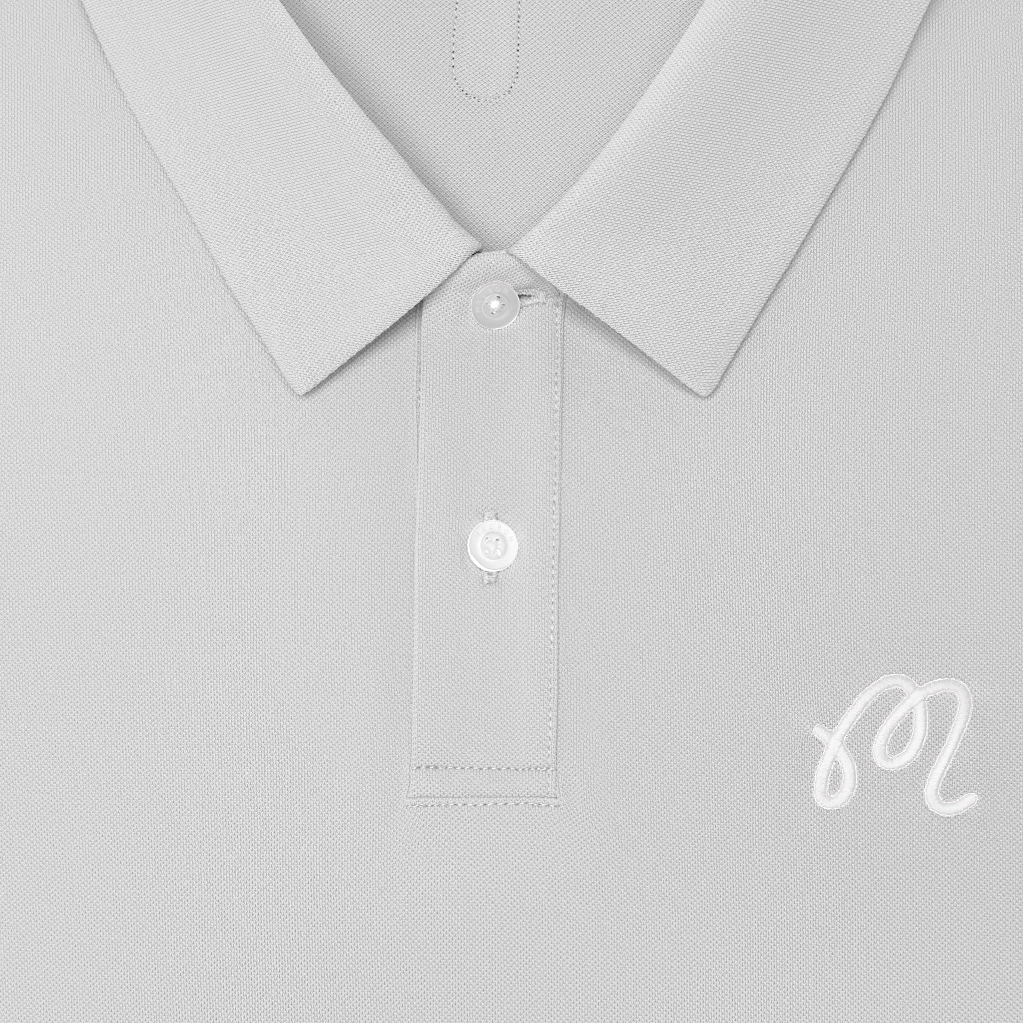 Close-up of a light gray polo shirt showing the collar, button placket, and a small white embroidered script logo on the chest.