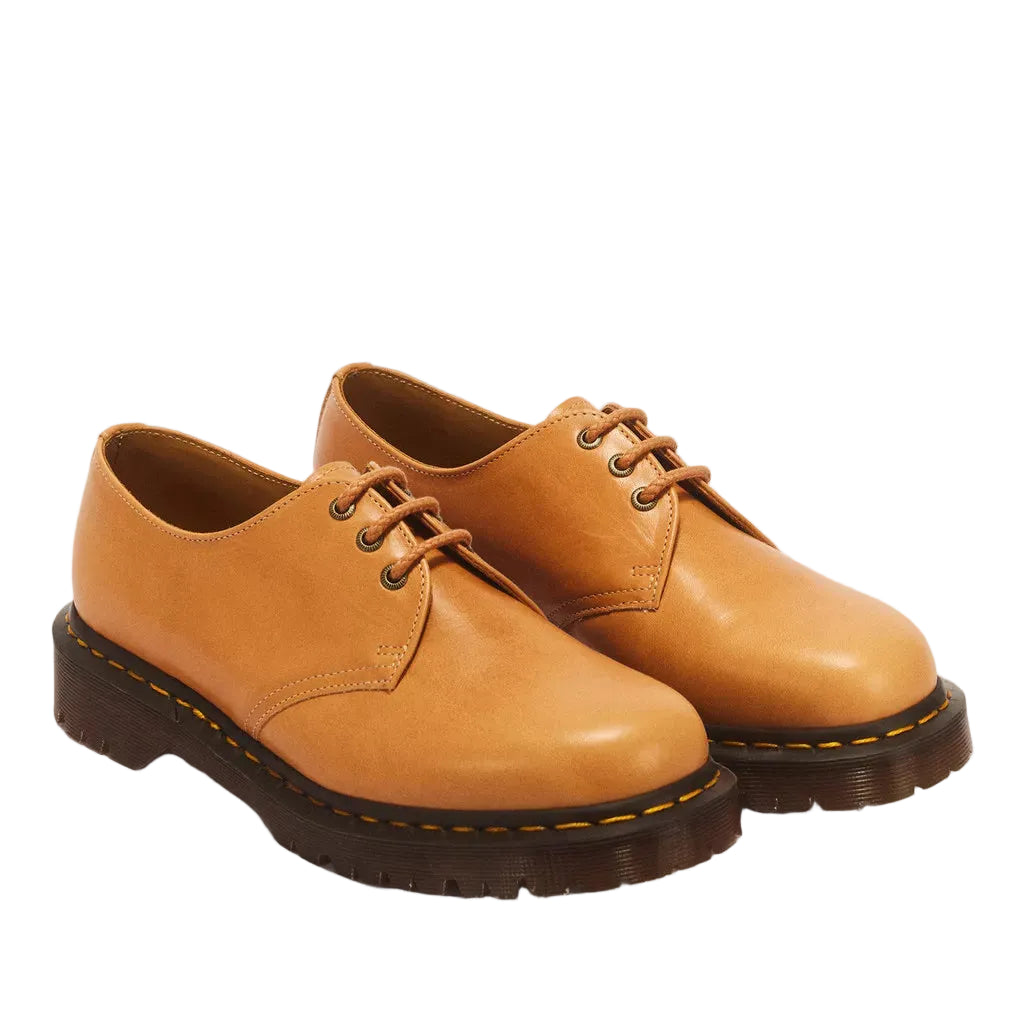 A pair of classic Dr. Martens 1-4-2 lace-up oxford shoes in tan leather with dark brown soles and yellow stitching, shown on a white background.
