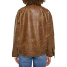 A person shown from the back wearing a brown faux-leather jacket decorated with gold star and flower embellishments, paired with blue jeans, against a plain white background.