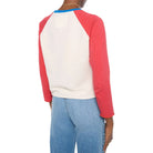 Person wearing a red and white baseball-style shirt with blue jeans on a white background