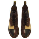 A pair of Dr. Martens lace-up ankle boots featuring a patchwork design of dark brown leather, tan suede, and black leather panels, shown from a top-down view on a white background.